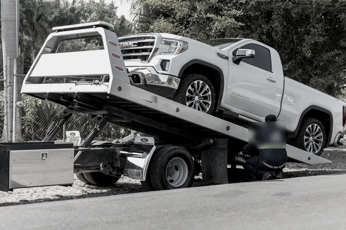 A flatbed tow truck loading a pickup truck at the roadside